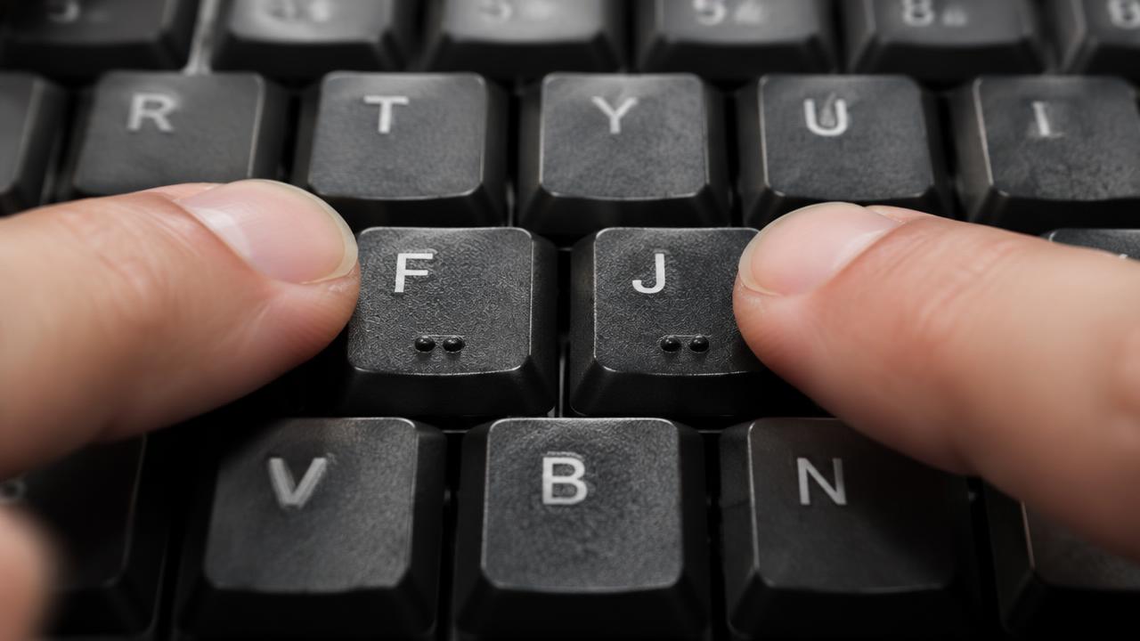 Dedos indicadores apoiados nas teclas F e J de um teclado preto